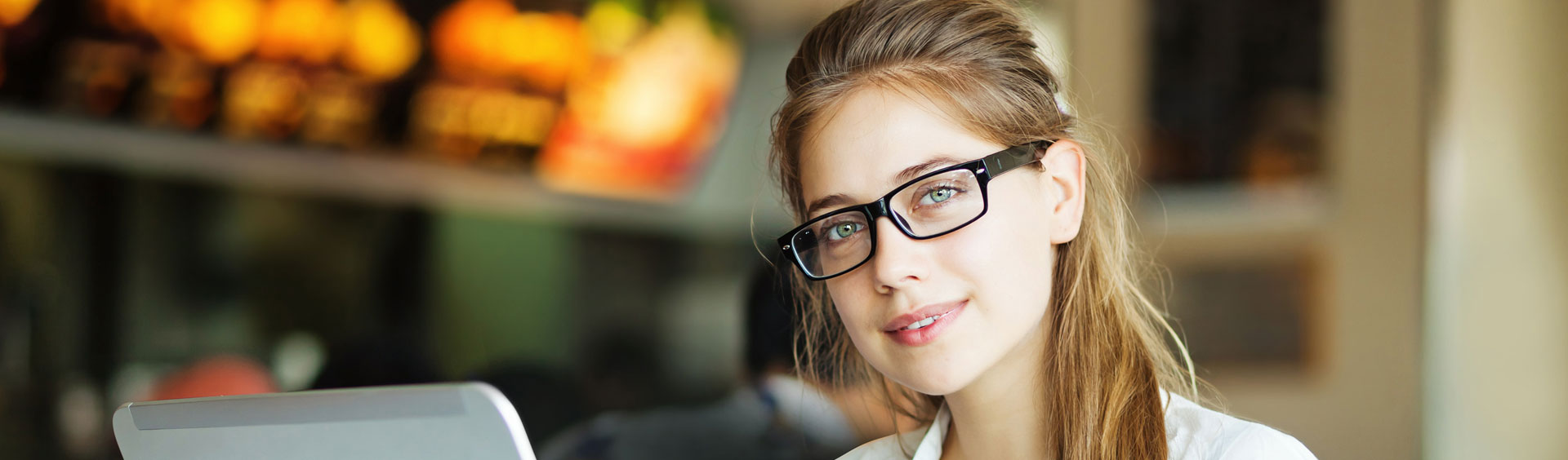 Jeune fille portant des lunettes derrière son ordinateur